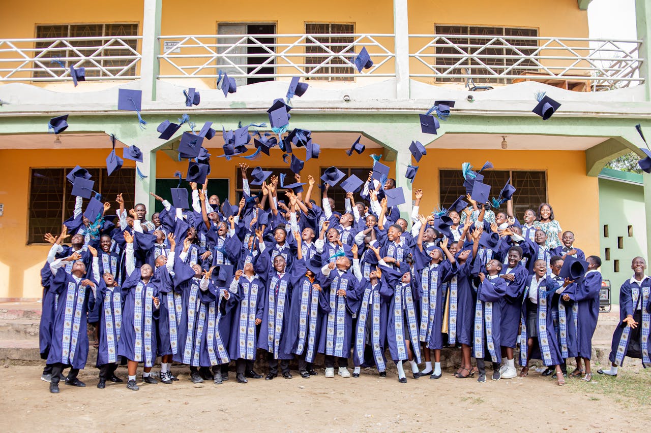 Group of graduates celebrating by tossing caps outside a building in Winneba, Ghana.